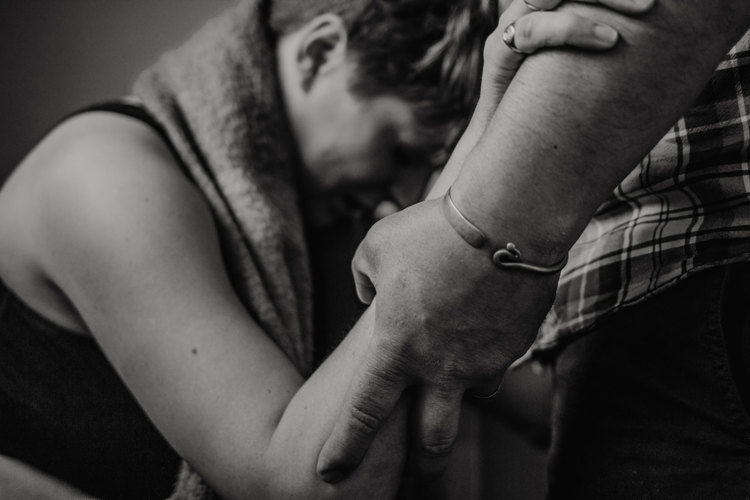 A woman in labour holding her partner's hand